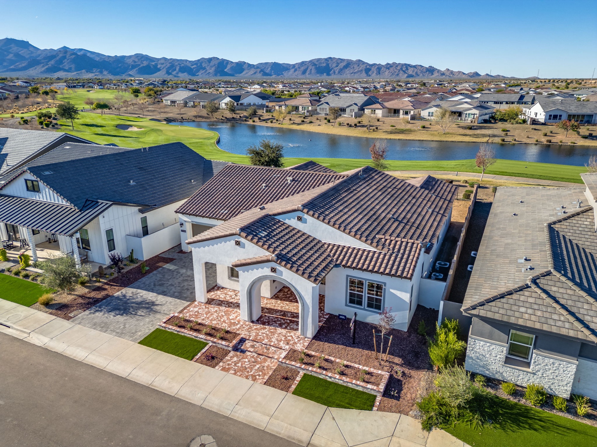 Aerial view of the home on the golf course with the lake and White Tank Mountains beyond