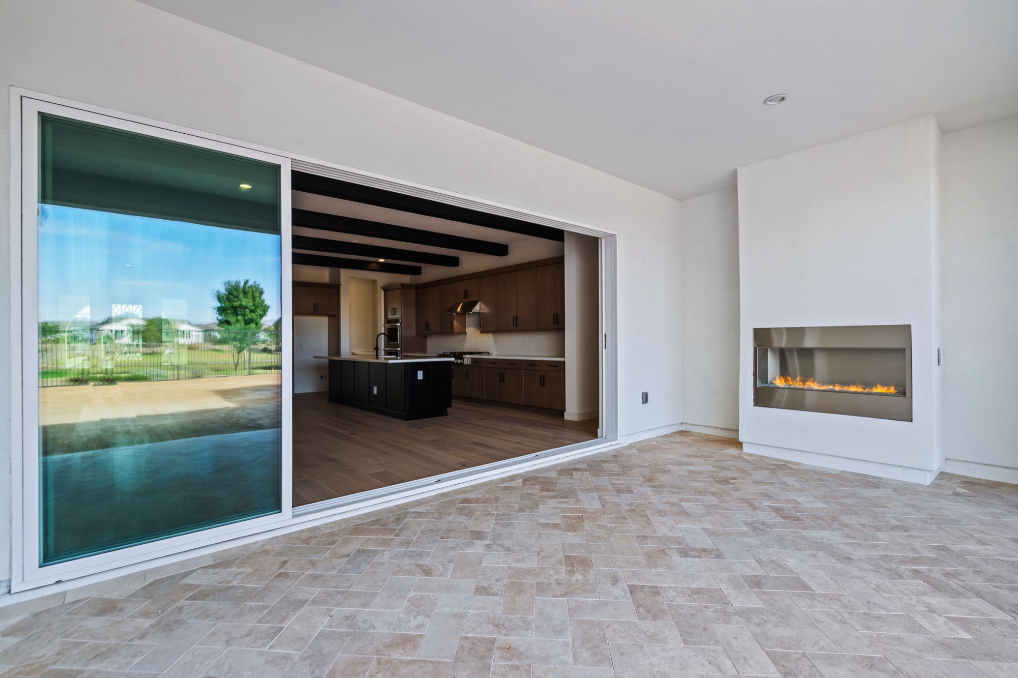 Covered patio with outdoor gas fireplace, open to the kitchen through stacking glass doors