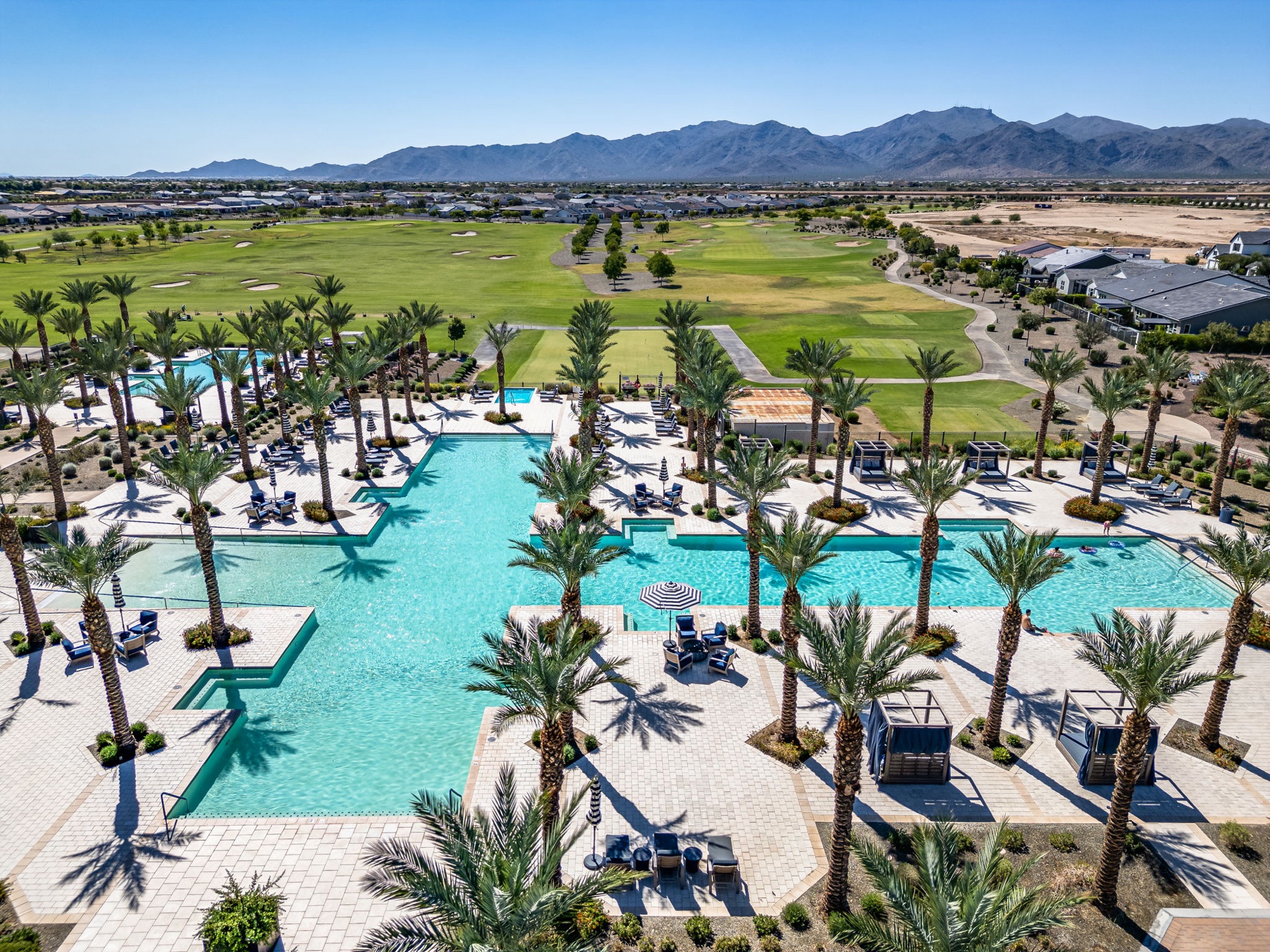 Sterling Grove resort pools, palm trees and the golf course with mountains beyond